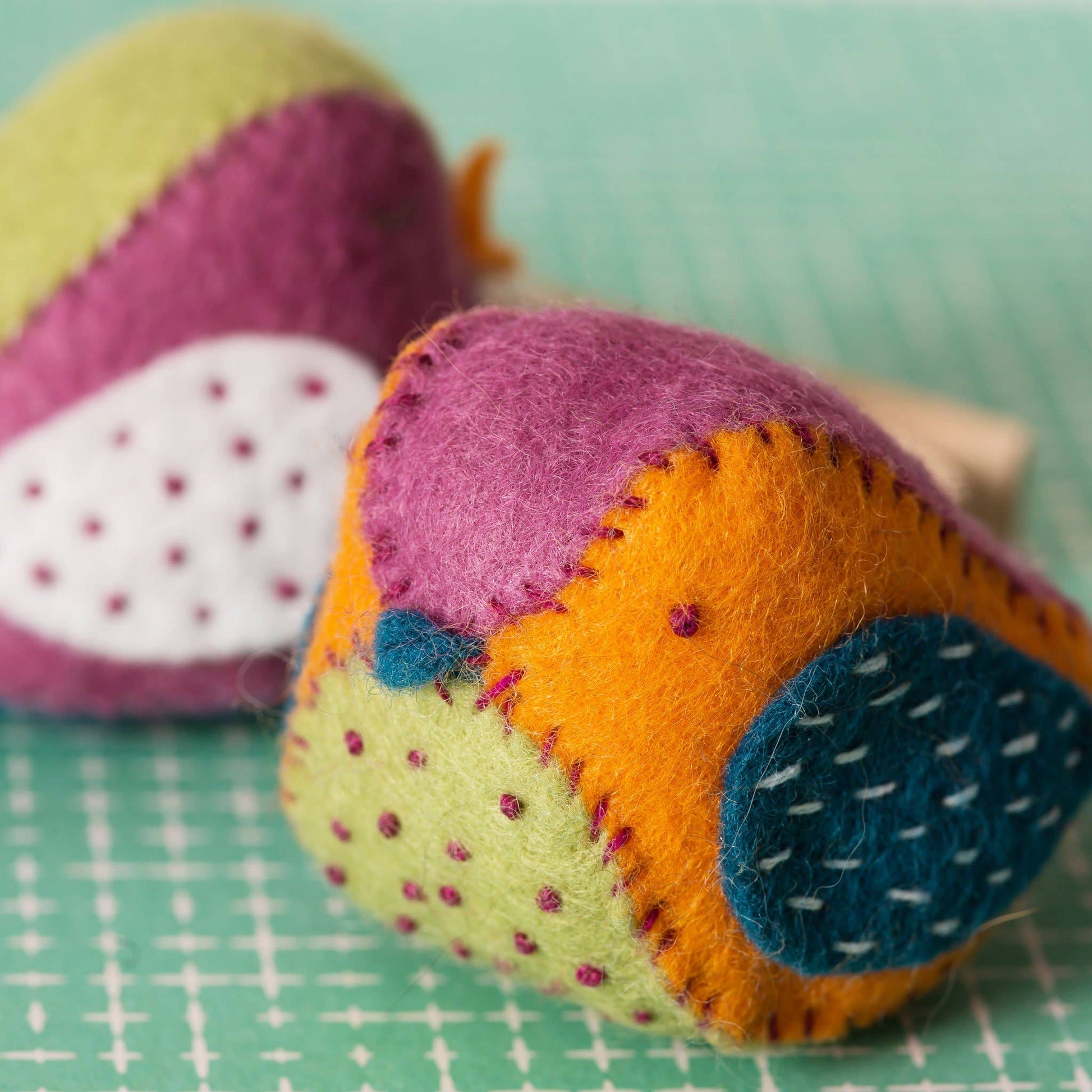 Colorful felt bird with geometric pattern on a green cutting mat