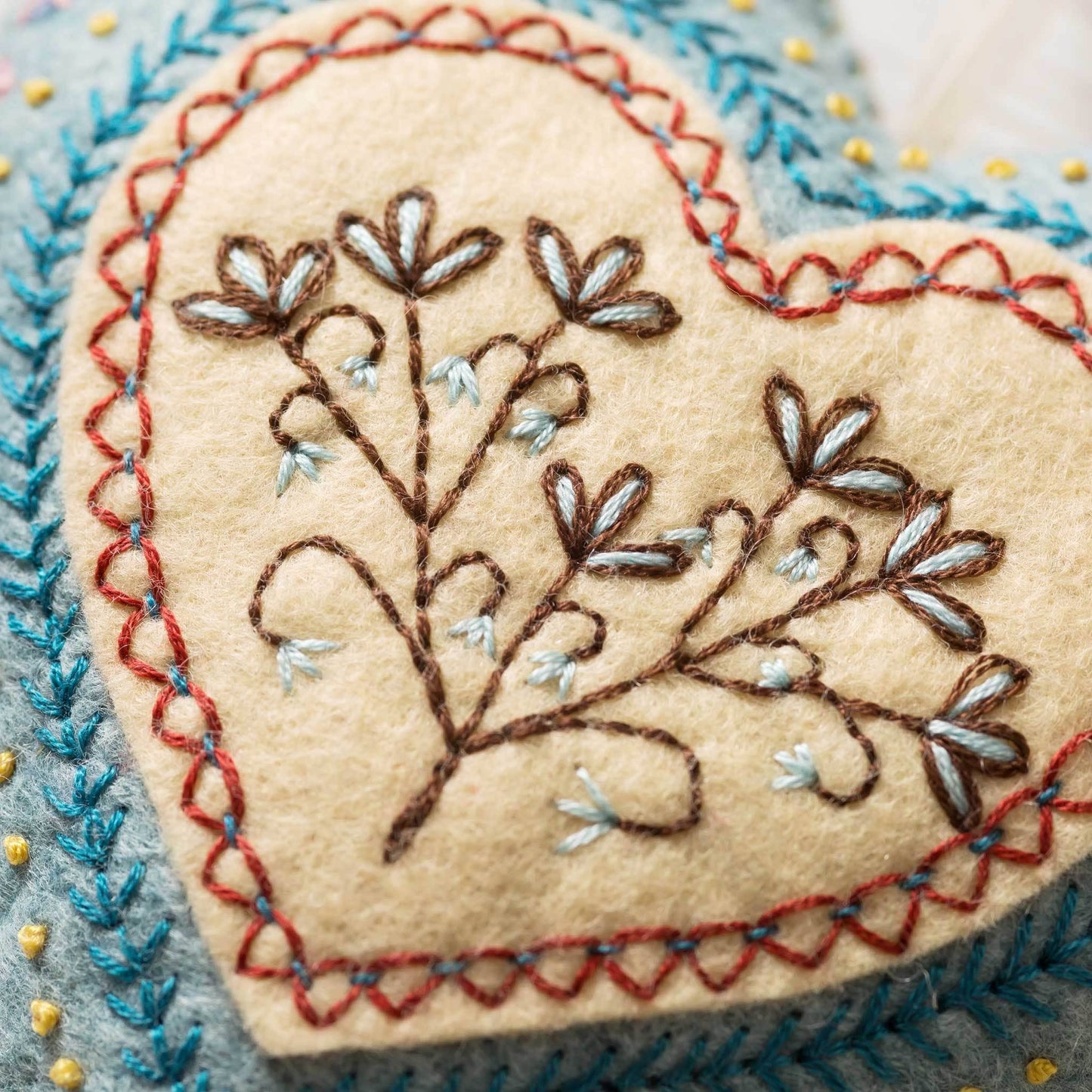 Heart-shaped embroidered patch with floral design on a textured background