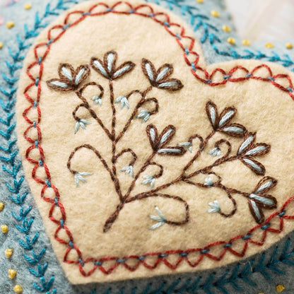 Heart-shaped embroidered patch with floral design on a textured background