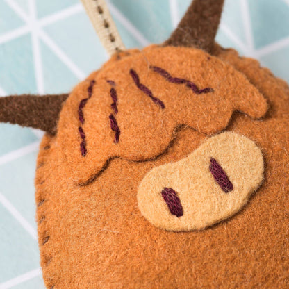 Close-up of a brown plush highland cow toy with a blurred background