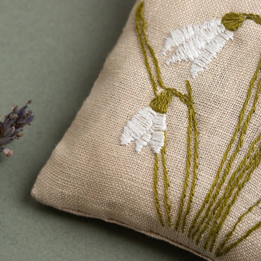 Embroidered linen pillow with a white floral design on a beige background