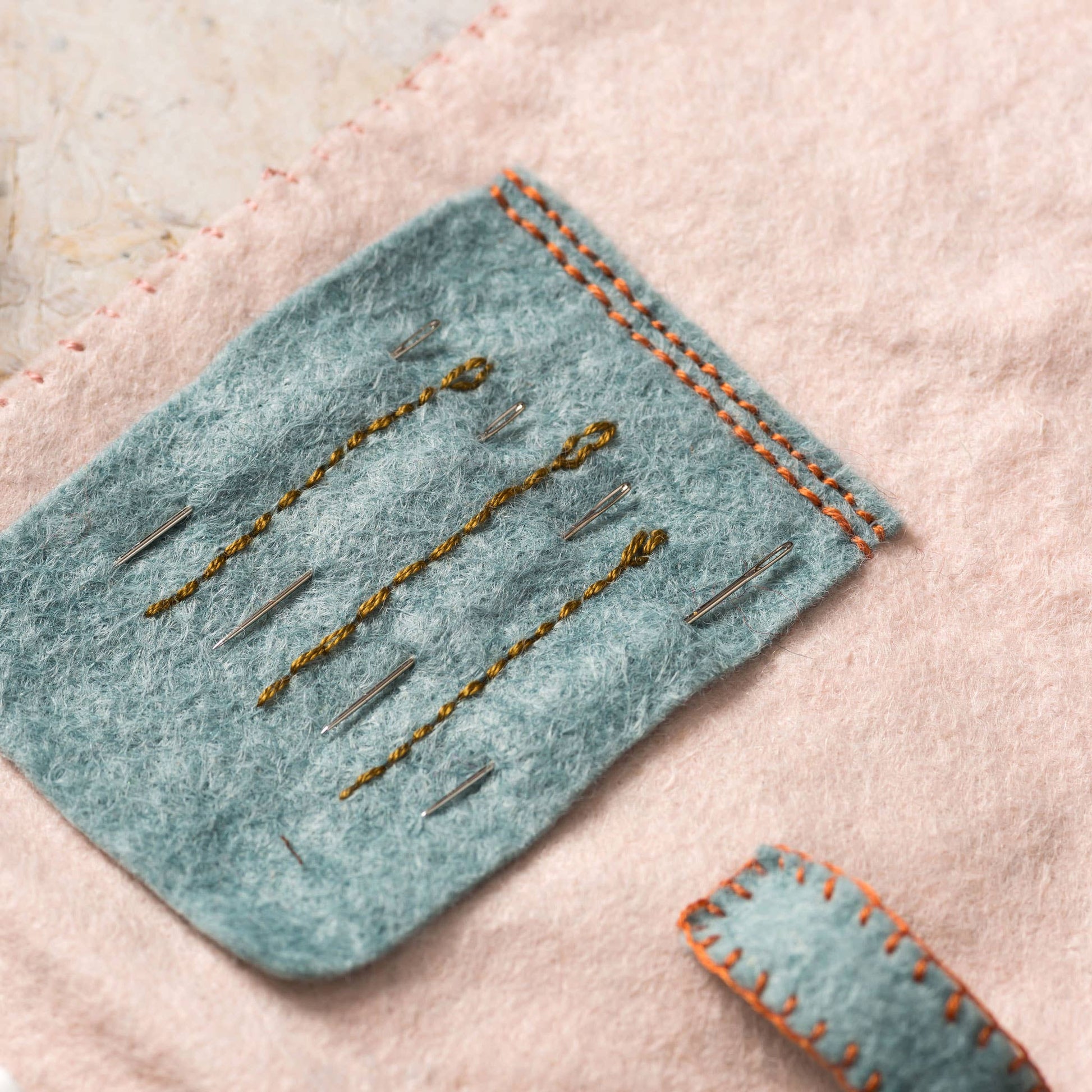 Felted fabric with embroidered details on a textured surface