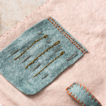 Felted fabric with embroidered details on a textured surface