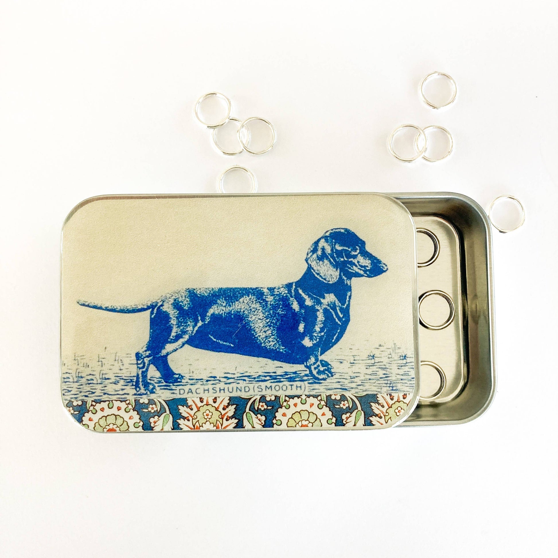 Tin box with a blue dachshund illustration on a beige background