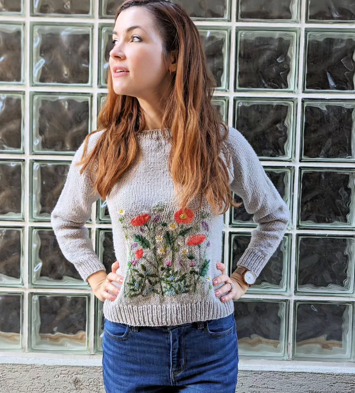 Woman wearing a sweater with floral design in front of a glass block wall