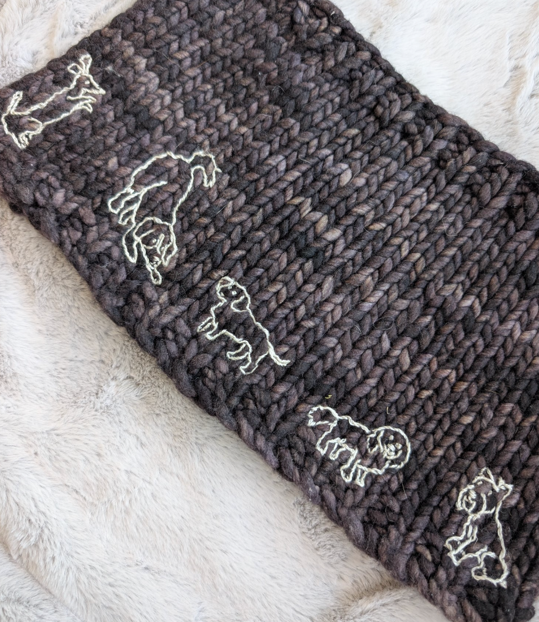 White dogs stitched onto a knitted scarf. 